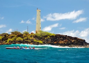 image of a racing canoe passing a lighthouse